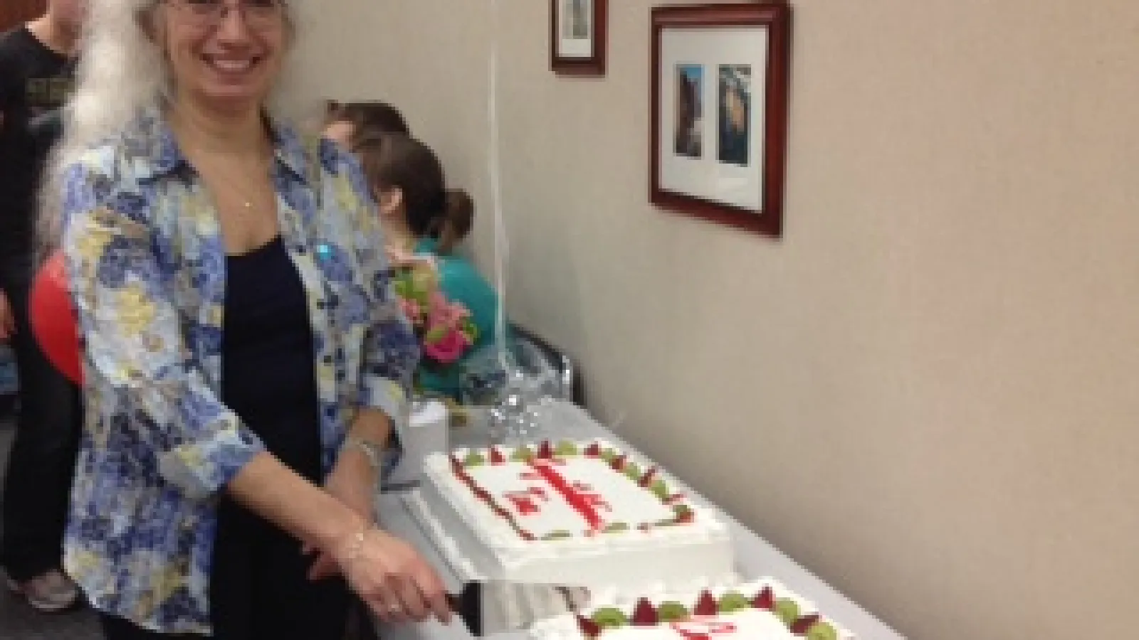 Dr. Tina Henkin cutting celebratory cake.