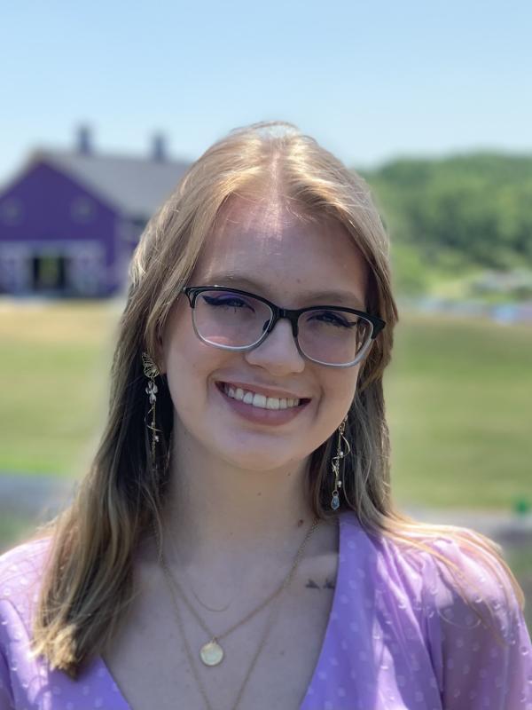 A woman smiles in front of a rural backdrop