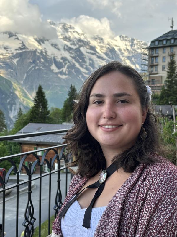A woman stands in front of mountains