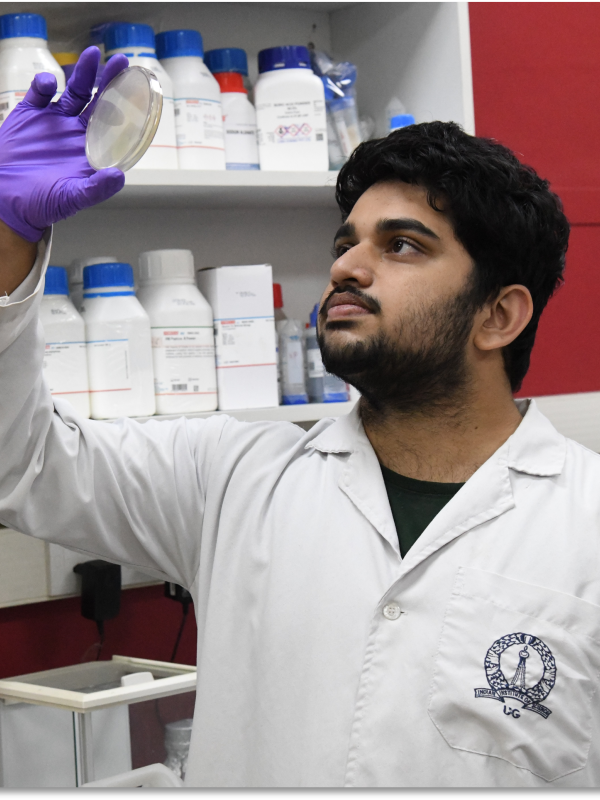 A man in a lab coat examines a specimen in a petri dish