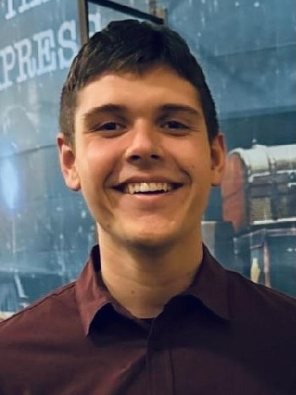 A photo of a man smiling  against a grey background