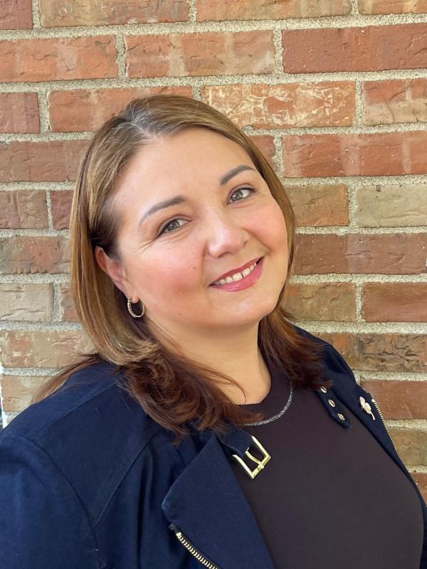 a smiling woman in front of a brick wall